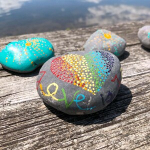 A rock painted with a heart and the word love in multiple colors.